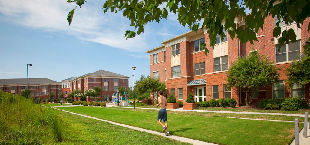 Student running in between a few of the apartment buildings in the Baity Hill Community. 